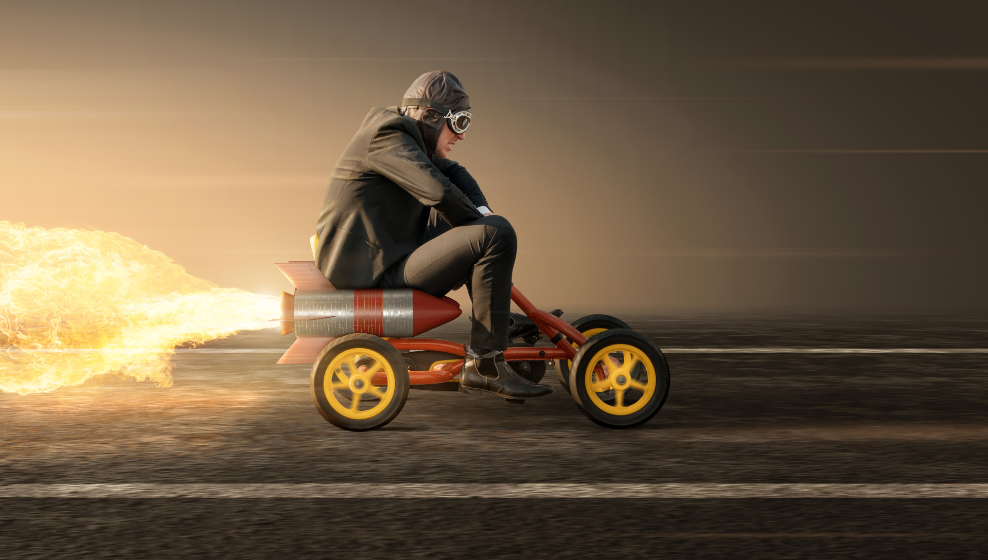 A businessperson in aviator goggles riding a pedal car fitted with a large rocket.